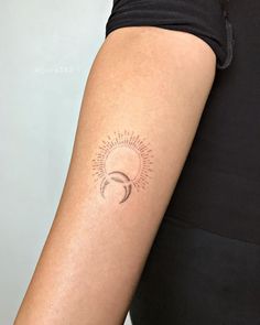 a woman's arm with a small sun and moon tattoo on her left arm