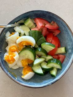 a bowl filled with cucumbers, tomatoes and hard boiled eggs