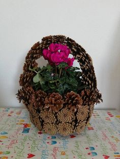 a basket filled with pine cones and flowers sitting on top of a colorful table cloth