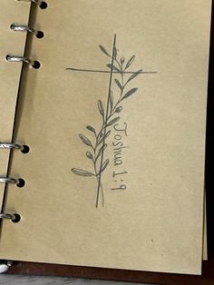 an open notebook with a cross drawn on the front cover and writing in black ink