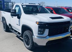 a white truck parked in a parking lot next to other trucks on display at a dealership