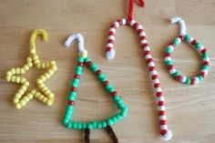 three christmas ornaments made out of candy canes on a wooden table with other items