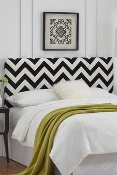 a bed with white sheets and black and white headboard