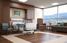 an empty hospital room with chairs, couches and a large window overlooking the mountains