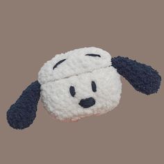 a white and black stuffed animal on a gray background with the head of a dog