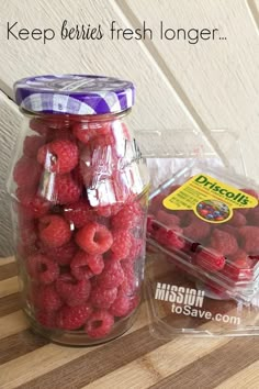 some raspberries are in a glass jar and on the table is a plastic bag