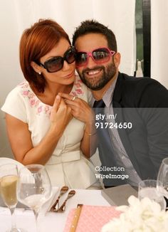 a man and woman sitting next to each other at a table with wine glasses on it