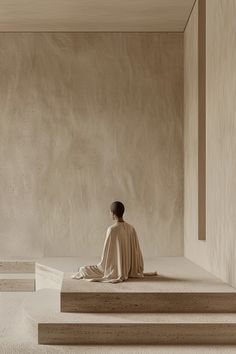 a person sitting on some steps in front of a wall and looking at the ground