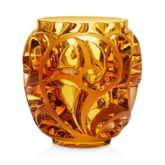 a golden vase sitting on top of a white surface with an intricate design in the center