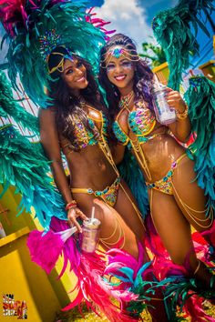 two women dressed in colorful costumes posing for the camera with one woman holding a bottle