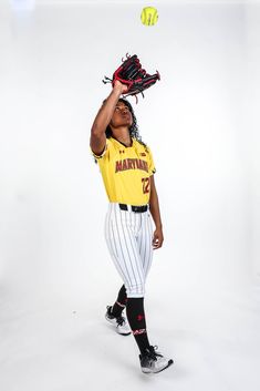 a baseball player holding a glove and ball up to his head while posing for the camera