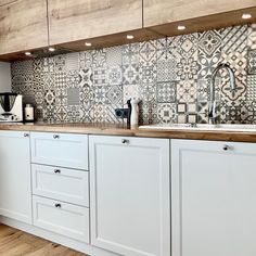 a kitchen with white cabinets and wooden counter tops, tiled backsplash above the sink