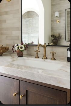 a bathroom sink with two faucets and a mirror in the backround