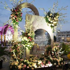 the entrance to an event with flowers and greenery on display in front of it