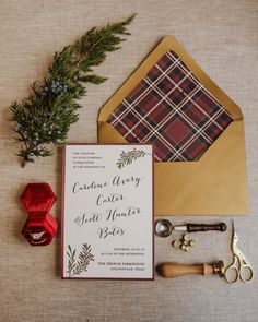 the wedding stationery is laid out on top of an envelope, scissors, and other items