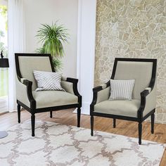 two chairs sitting next to each other on top of a rug in front of a window