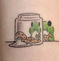 a tattoo with an image of a fish in a jar and cookies on the ground