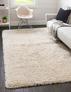 a living room with a white couch, chair and rug on top of the floor