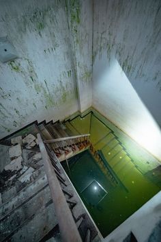 an abandoned building with water in the floor and stairs leading up to the second floor