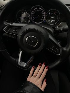 a woman's hand on the steering wheel of a car with gauges and dash lights