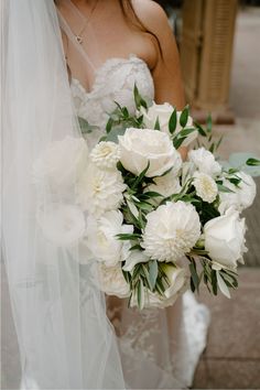 a bride holding a bouquet of white flowers