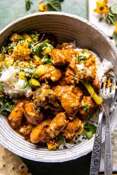 a bowl filled with rice and chicken next to a fork