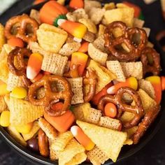 a bowl full of halloween snack mix with pretzels, candy corn and jack - o'- lanterns