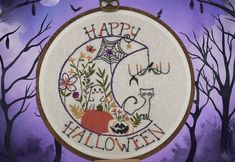 a cross stitch pattern with the words happy halloween written on it in front of some trees