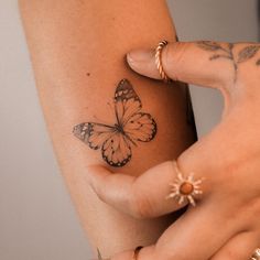 a woman's arm with a butterfly tattoo on the left side of her arm