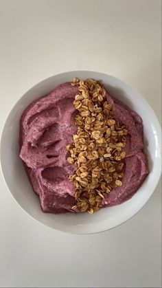 a white bowl filled with purple and oatmeal on top of a table