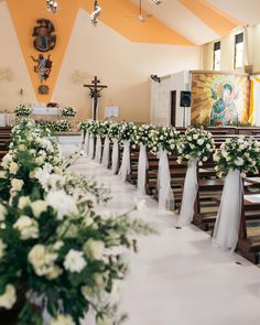 the aisle is lined with white flowers and greenery