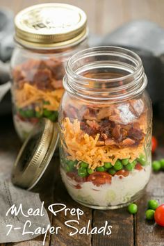 two mason jars filled with food sitting on top of a wooden table