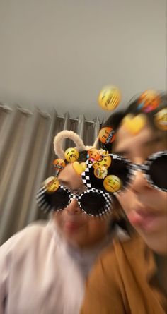 two people wearing mickey mouse ears and sunglasses with smiley faces drawn on them's hats