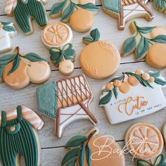 some decorated cookies are laying on a white wooden table with green leaves and oranges