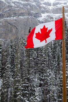 a canadian flag flying in front of snow covered mountains