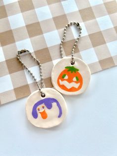 two pendants with different designs on them sitting on a checkered tablecloth background