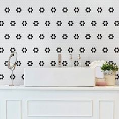 a white sink sitting next to a wall with black flowers on it