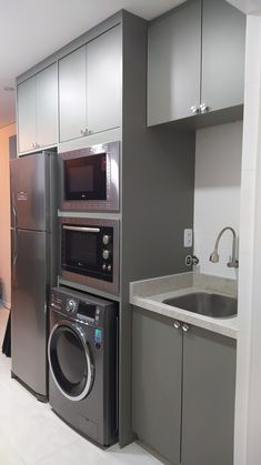 a kitchen with stainless steel appliances and white tile flooring, along with gray cabinets