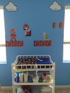 a baby's room decorated in blue and white with mario bros wall decals