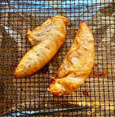 two pieces of chicken sitting on top of a grill