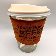 a coffee cup sitting on top of a white table next to a brown paper container