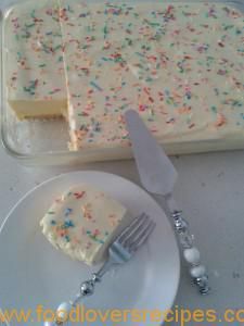 a piece of cake with white frosting and sprinkles next to a fork