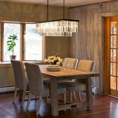 a dining room table with chairs and a chandelier hanging from it's ceiling