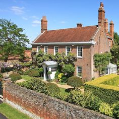 a large brick house surrounded by hedges and trees