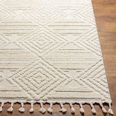 a large white rug with tassels on top of wooden floor next to wood flooring