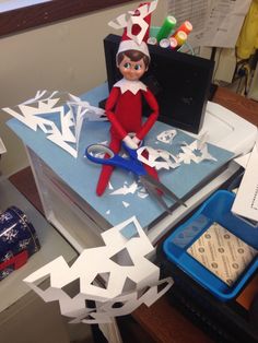 an elf is sitting on top of a box with scissors