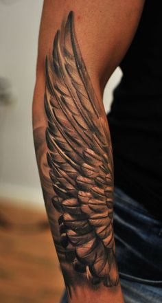 a man's arm with an angel wing tattoo on it