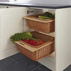 two wicker baskets with vegetables in them sit on the corner of a kitchen counter