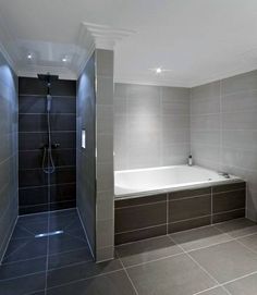 a bathroom with a walk in shower next to a white bath tub and tiled walls