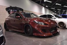 three different colored cars are parked in a showroom